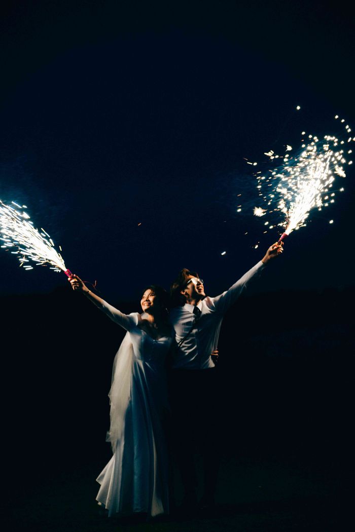 Bride and groom celebrate their wedding night with sparklers under the stars, capturing a magical moment.