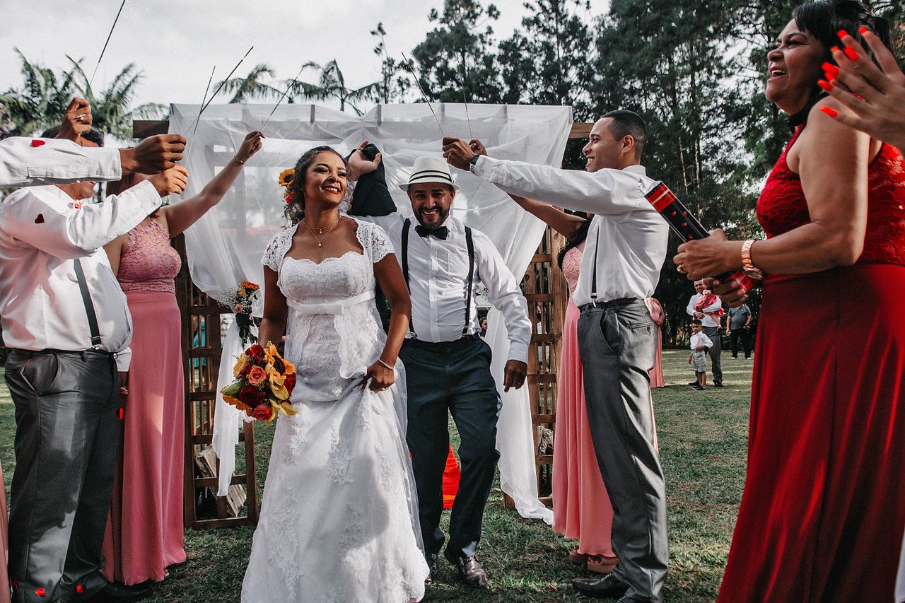 A vibrant and cheerful outdoor wedding ceremony featuring a smiling bride and groom surrounded by guests.